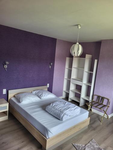 une chambre avec un grand lit et un mur violet dans l'établissement La maison du cœur, à Saint-Moreil
