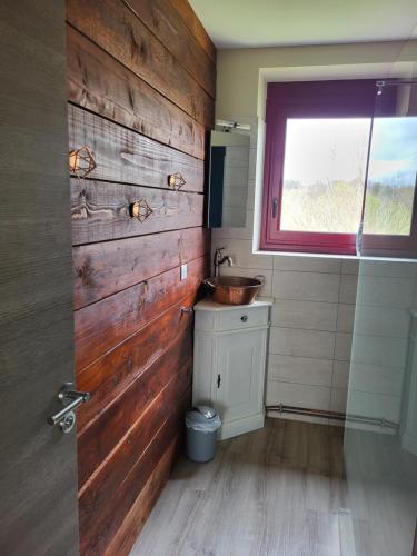 a bathroom with a sink and a wooden wall at La maison du cœur in Saint-Moreil
