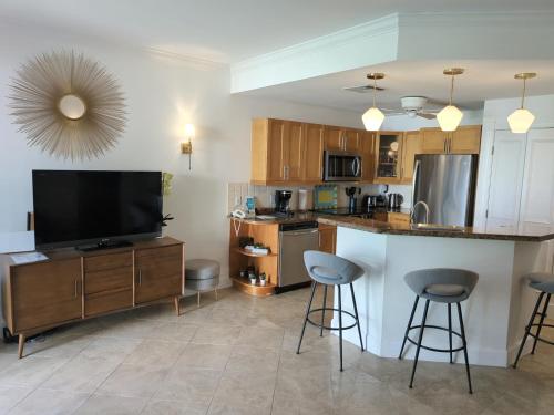 a kitchen with a television and a counter with stools at Villa Renaissance Grace Bay in The Bight Settlements