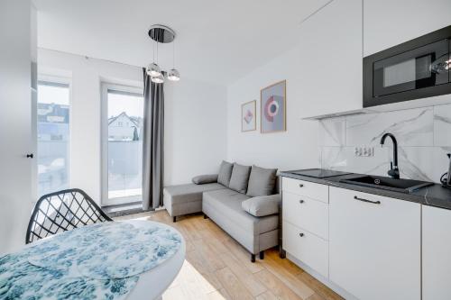 cocina y sala de estar con sofá y mesa en Carbon by OneApartments, en Sopot
