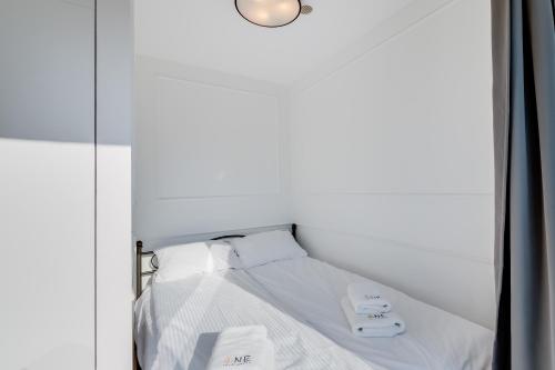 a bed with white sheets and white towels on it at Carbon by OneApartments in Sopot