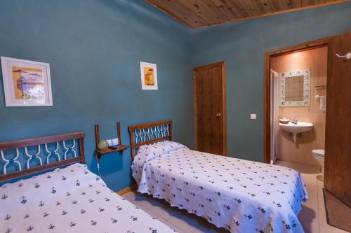 1 dormitorio con 2 camas y baño con lavamanos en Camping Anzánigo en Anzánigo