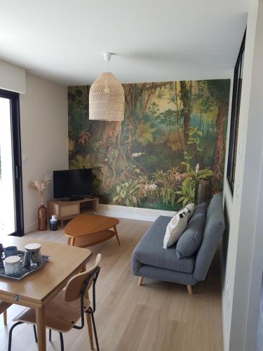 una sala de estar con un sofá y una mesa en Au Petit Manoir, en Montbert
