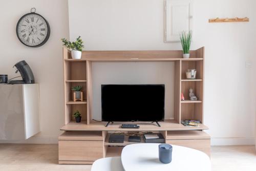 een woonkamer met een tv op een houten entertainmentcentrum bij Bike's House - Au coeur de Royat in Royat