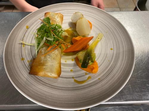 a plate of food with vegetables on a table at Logis Hôtel La Bastide De Grignan & Restaurant "La Chênaie" in Grignan