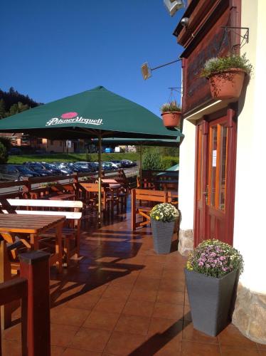 a restaurant with wooden tables and a green umbrella at Hotel Terasa in Vimperk