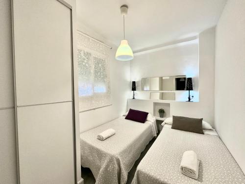 a white room with two beds and a mirror at Kinahouse in Córdoba
