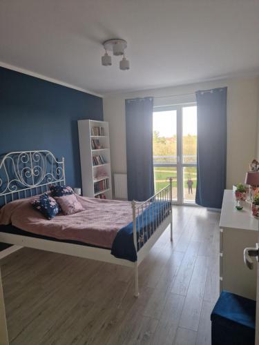 a bedroom with a bed and a large window at Słoneczny Apartament in Suwałki