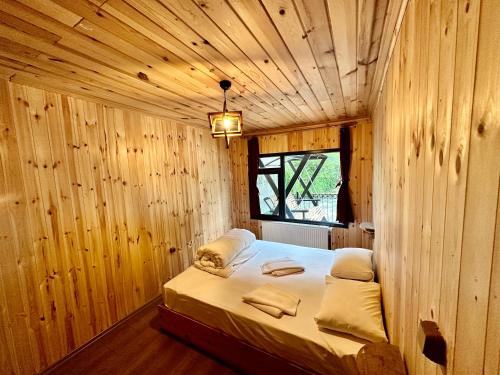 1 dormitorio con 1 cama en una habitación de madera en TUVA VİLLA Bungalov, en Çamlıhemşin