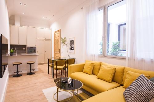 ein Wohnzimmer mit einem gelben Sofa und einer Küche in der Unterkunft Indulge in Seville C in Sevilla