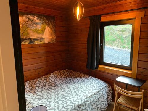 ein Schlafzimmer mit einem Bett in einer Hütte mit einem Fenster in der Unterkunft Gîtes Douillets : Chalet sur Pilotis in Houyet