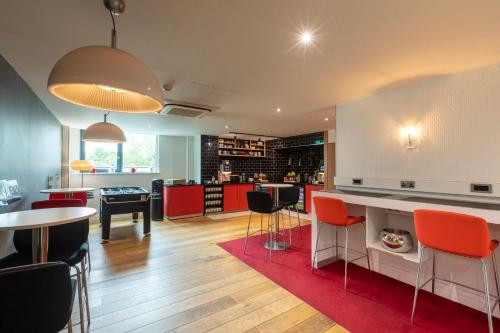 a kitchen with red and black tables and chairs at Crowne Plaza Birmingham NEC by IHG in Bickenhill