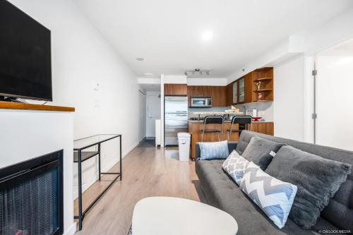 a living room with a gray couch and a kitchen at Modern DT Vancouver 1BD Condo in Vancouver