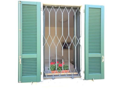 a window with green shutters and a window with flowers at Hotel Villa San Fedele in San Fedele Intelvi