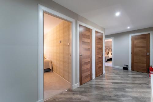 um corredor com portas de madeira e pisos em azulejo em Gleneagles Apartment - Guthrie Court Gleneagles em Auchterarder