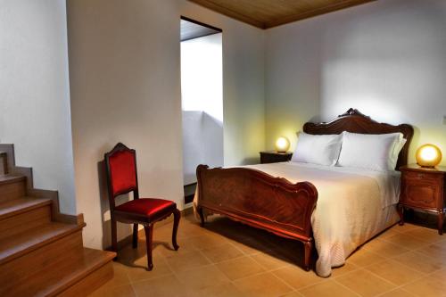een slaapkamer met een bed en een rode stoel bij Casa do Médico in Carção