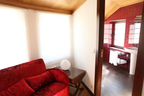 a living room with a red couch and a bathroom at Casa do Médico in Carção