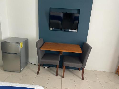un tavolo e due sedie e una televisione in una stanza di Hotel Real Villa a Villa Corona
