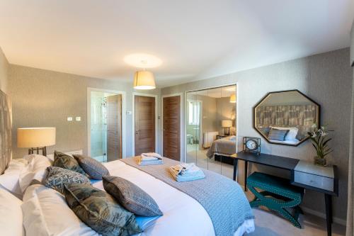 een slaapkamer met een groot bed en een spiegel bij Gleneagles Apartment - Guthrie Court Gleneagles in Auchterarder