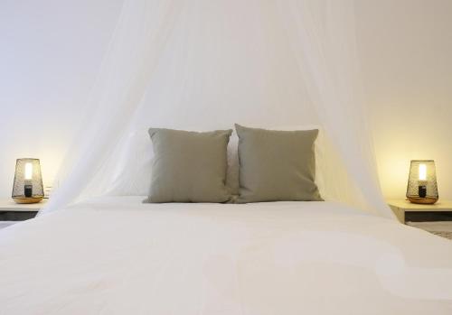 ein weißes Bett mit zwei Kissen und zwei Lampen in der Unterkunft EDEN RENTALS Rincón Cozy in Taco
