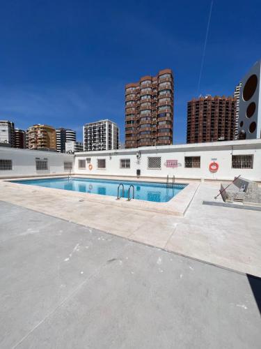 a swimming pool in front of a building with tall buildings at Hany apartment Ducado 7-C in Benidorm