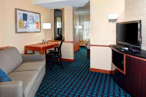 a hotel room with a couch and a table and a television at Fairfield Inn & Suites by Marriott Anniston Oxford in Oxford