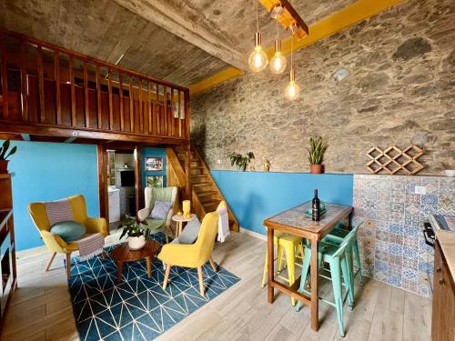 a living room with a wooden table and yellow chairs at Victoria Tiny Stone House in Ponta do Pargo