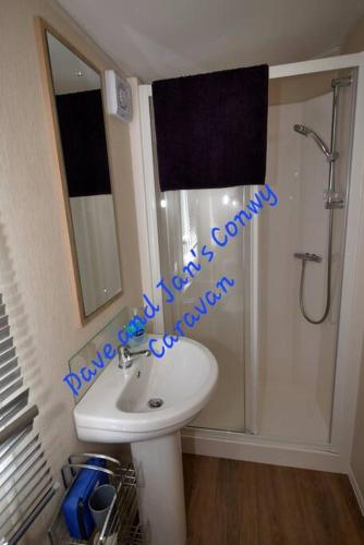 a bathroom with a sink and a shower with a mirror at Dave and Jan's Conwy Caravan-Bryn Morfa in Deganwy