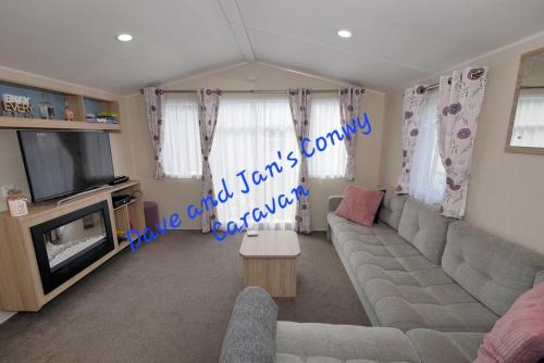 a living room with a couch and a tv at Dave and Jan's Conwy Caravan-Bryn Morfa in Deganwy