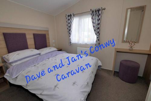 Dave and Jan's Conwy Caravan-Bryn Morfa في ديجانوي: غرفة نوم مع سرير مع وضع علامة عليه