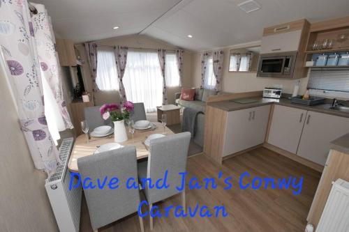 a kitchen and living room with a table and chairs at Dave and Jan's Conwy Caravan-Bryn Morfa in Deganwy