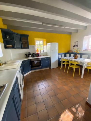 une cuisine avec des armoires bleues et une table avec des murs jaunes dans l'établissement Les Bruyères Rebecca, à Pleugueneuc