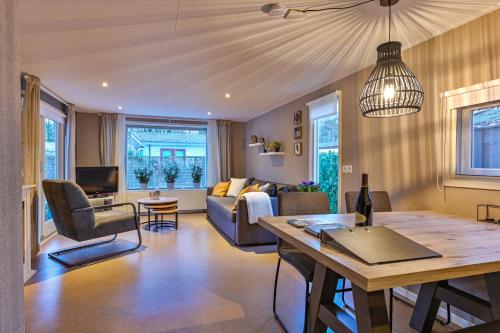a living room with a couch and a table at Ruime luxe 4 persoons Chalet midden op de Veluwe in Hoenderloo