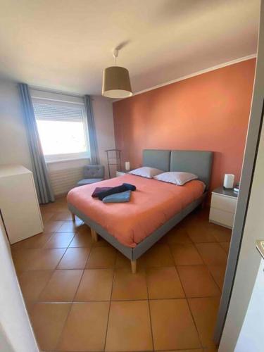 une chambre avec un lit avec un mur orange dans l'établissement Logement idéal pour un séjour alsacien en amoureux, à Colmar