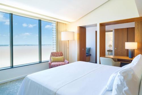 a hotel room with a bed and a chair and windows at The Westin Galleria Dallas in Dallas