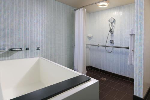 a bathroom with a tub and a shower with blue tiles at The Westin Galleria Dallas in Dallas