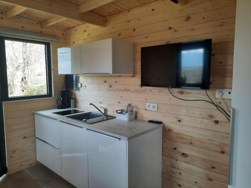 eine Küche mit einem Waschbecken und einem TV in einer Hütte in der Unterkunft La roulotte de Soiron in Pepinster