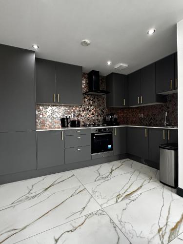 a kitchen with black cabinets and a marble floor at Two bed apartment with balcony Slough,Windsor,Legoland in Slough