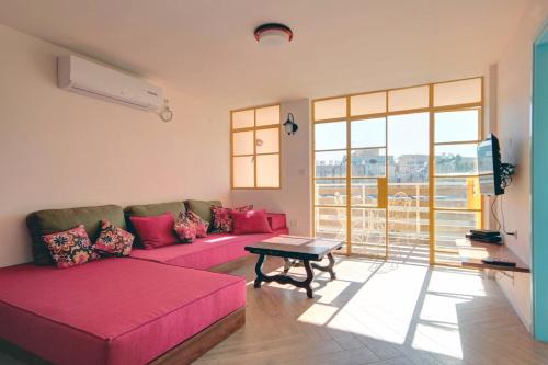 sala de estar con sofá rosa y mesa en Golda Vacation Rentals, en Jerusalén