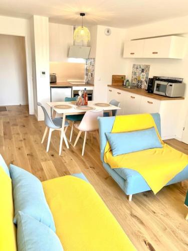 un salon avec des chaises jaunes et bleues et une cuisine dans l'établissement La Plagerie Front de Mer, à Fort-Mahon-Plage