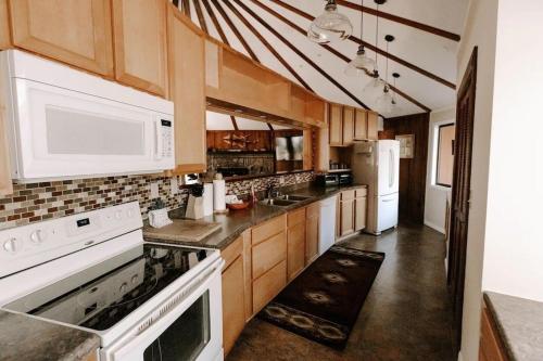 a kitchen with white appliances and wooden cabinets at Cabin with Treehouse Views, 3 King Beds, 4 Bunks, and Large Hot Tub! in Gatlinburg
