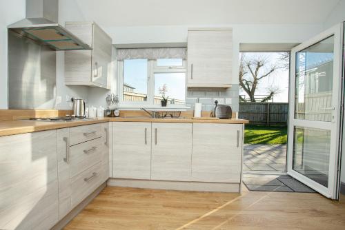 a kitchen with white cabinets and a large window at Willow Cottage a quaint holiday cottage in Wigtoft Boston Lincolnshire in Boston