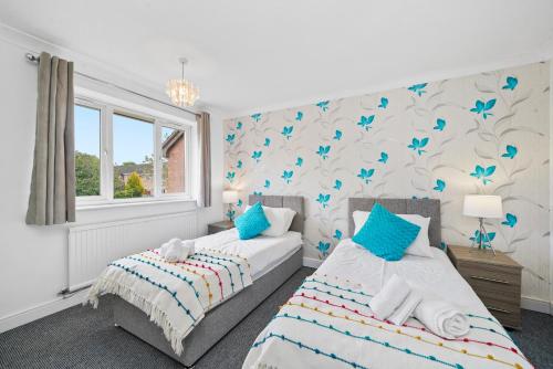 two beds in a bedroom with blue butterflies on the wall at Three Bedroom Home Near Central Milton Keynes by HP Accommodation with Free Parking, WiFi & Sky TV in Milton Keynes