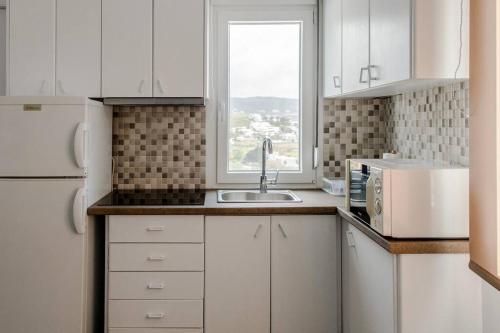 cocina blanca con fregadero y ventana en Harmony Apartment 2, en Agios Sostis