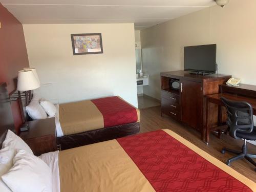 a hotel room with two beds and a desk and a television at King's Inn Motel in Reading