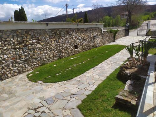 a stone retaining wall with a green lawn at SmallHotel - Vevi in Vévi