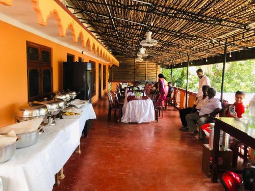 a restaurant with tables and people in a room at Thisha Hotel & Restaurant in Jaffna