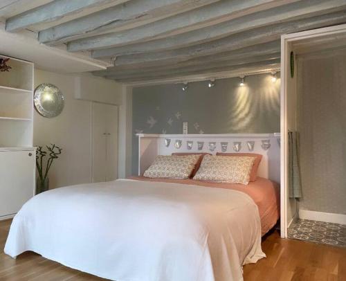une chambre avec un grand lit blanc dans une pièce dans l'établissement Beau studio Gare de Lyon, à Paris