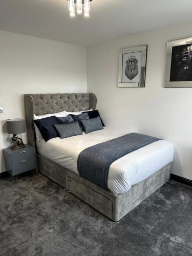 um quarto com uma cama grande e almofadas azuis em Two bed apartment with balcony Slough,Windsor,Legoland em Slough