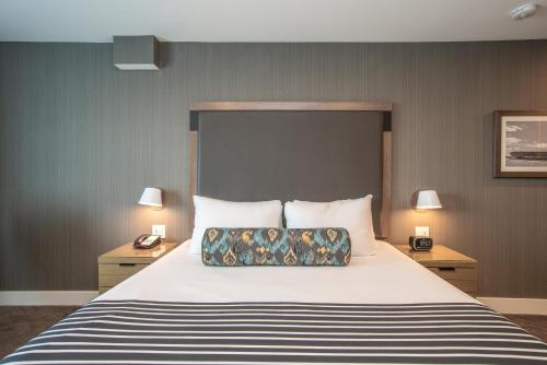 a bedroom with a large bed with two night stands and two lamps at Sandman Signature Ottawa Airport Hotel in Ottawa